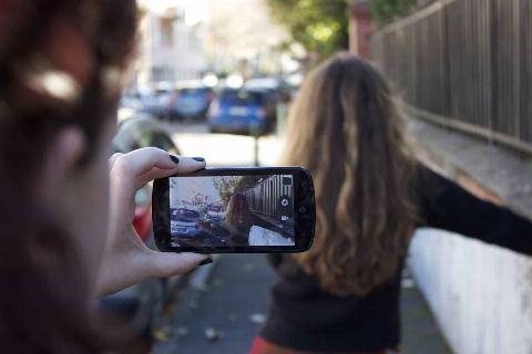 Un smartphone en train de filmer une personne dans une rue, lors d’un atelier de tournage au portable