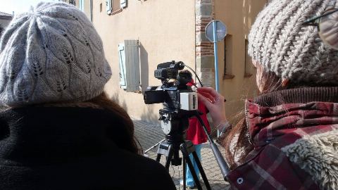 Deux personnes filment avec une caméra sur trépied, pendant un atelier en extérieur