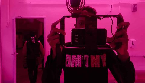 Face à un miroir, une personne filme au téléphone monté sur une cage de tournage